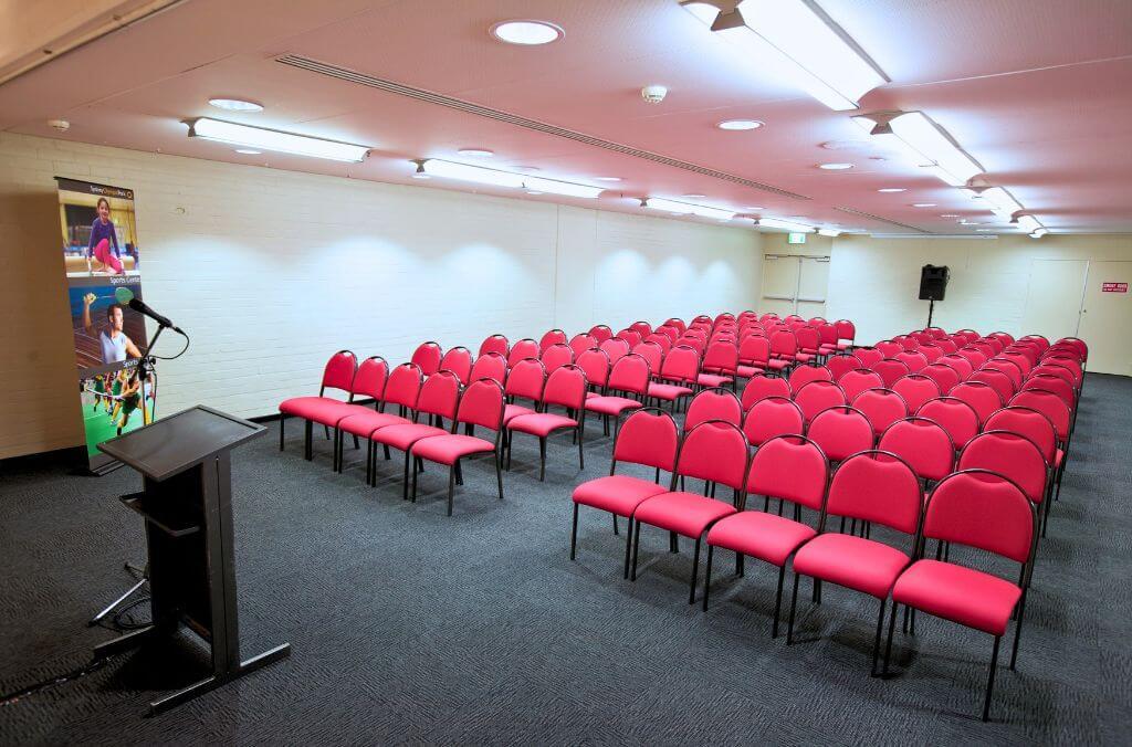 Acacia and Banksia conference room, large room lined with red chairs and a microphone and podium at the front
