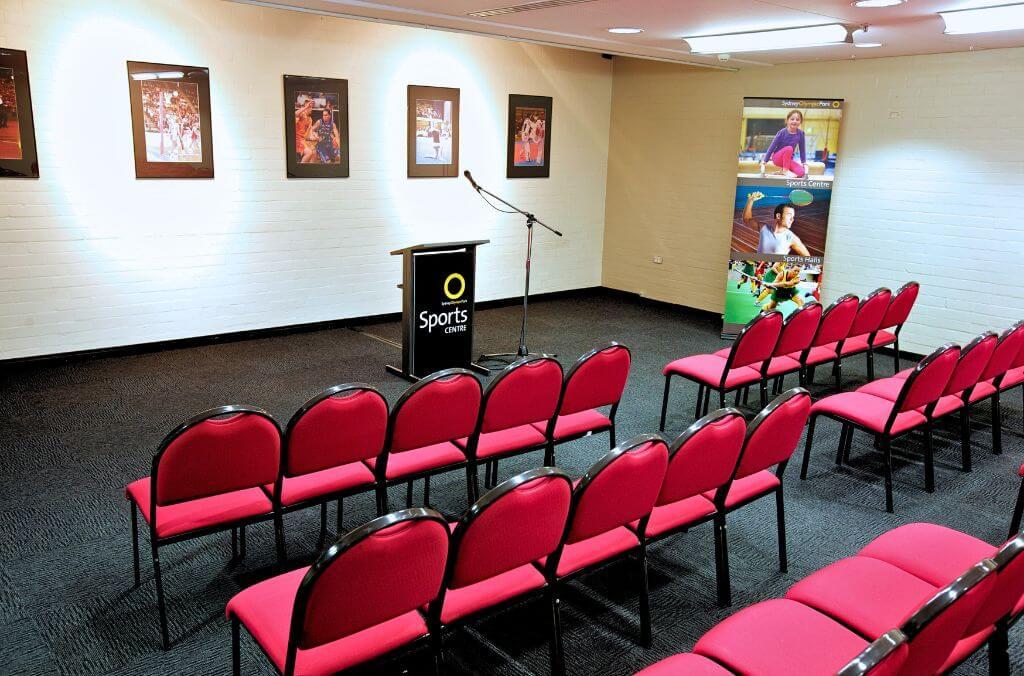 Acacia and Banksia conference room, large room lined with red chairs and a microphone and podium at the front